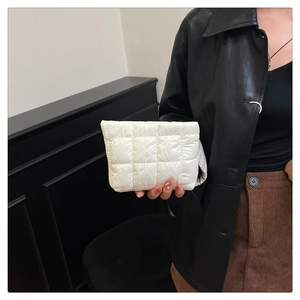 Detail of white quilted puffer clutch bag with square stitching and soft nylon texture