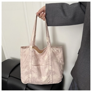 Detailed close-up of pink floral canvas tote bag featuring front pocket and dual handles