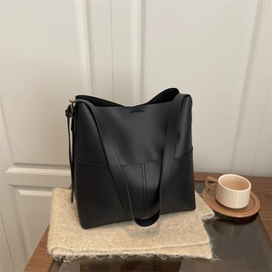 Minimalist black matte leather bucket shoulder bag with spacious design on soft fabric