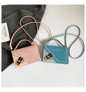 Detail view of pink and teal textured leather crossbody bags with gold metal clasps
