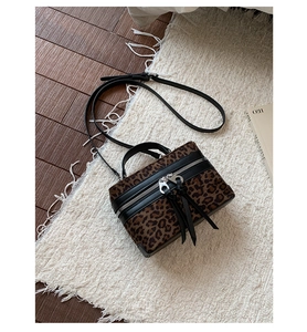 Détail du sac à main imprimé léopard avec bordure en cuir et pompon décoratif à franges