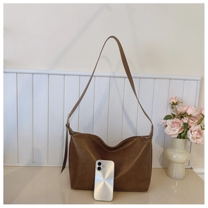 Detail view of a large brown hobo bag showing faux leather texture and adjustable strap