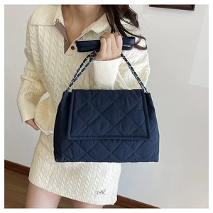 Detail of navy blue quilted shoulder bag with silver chain strap and leather material