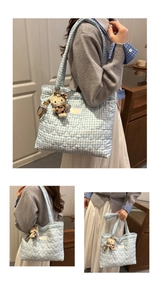 Detailed view of light blue gingham tote bag with heart quilting and plush cat charm
