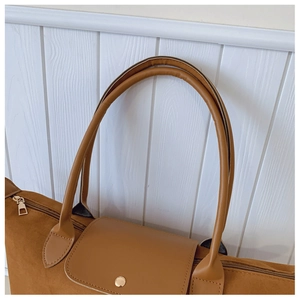 Detailed close-up of brown suede tote bag featuring premium leather handles and golden metal hardware