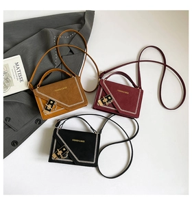 Close-up of stylish contrast stitch crossbody bags in brown, burgundy, and black suede finish