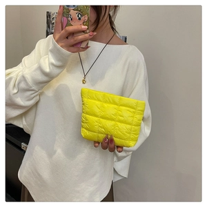 Detailed shot of fluorescent yellow quilted clutch bag with soft down-like padded texture
