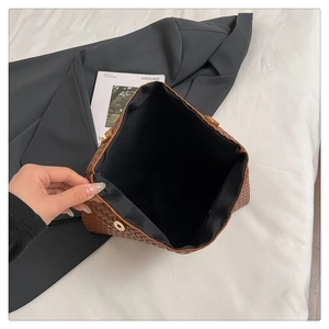 Dettaglio borsa in pelle intrecciata marrone scuro con fibbia dorata e interno ampio