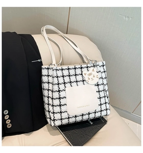 Detail of checkered tote bag with white front pocket and cute tiger head charm
