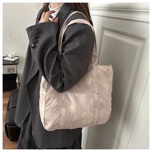 Close-up of floral canvas tote bag with side pocket worn by model in gray blazer