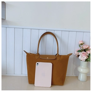 Brown suede tote bag shown next to a tablet to demonstrate its large storage capacity