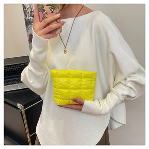 Detail of bright yellow quilted clutch bag with vibrant puffer down nylon texture