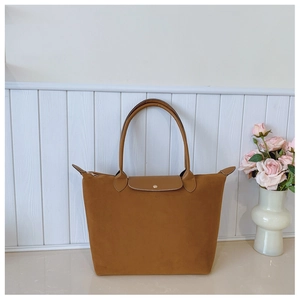 Detail of camel suede tote bag showing leather flap closure and sturdy top handles