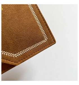 Vue macro d'un sac bandoulière en daim marron avec coutures tissées blanches et texture