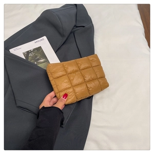 Detail of yellow quilted puffer clutch featuring a grid pattern and soft padded texture
