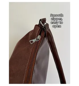 Detail of smooth metal zipper and premium frosted leather stitching on coffee hobo bag