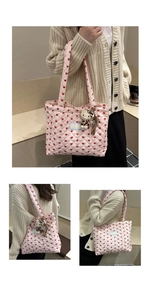 Close-up of pink quilted tote bag featuring red heart patterns and plush bear charm