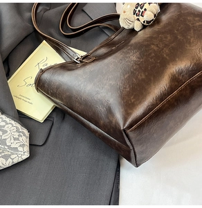 Close-up of dark brown vintage leather tote bag with oil-wax texture and uniform stitching