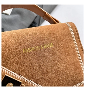Gros plan du sac à main en daim marron avec coutures blanches et boucle dorée