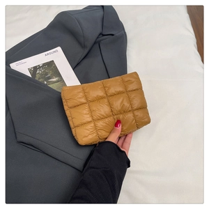 Close-up of brown quilted down fabric clutch with minimalist large grid texture