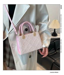 Detail of woven handle and pleated texture on pink crossbody bag with gold hardware