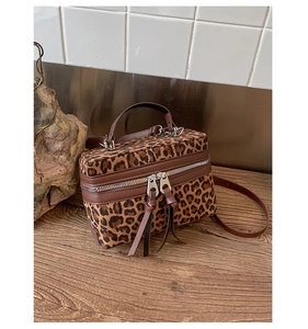 Détail macro d'un sac boîte imprimé léopard avec bordure cuir et double fermeture