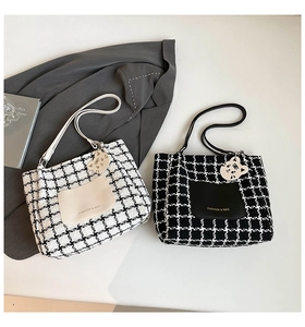 Detail of tweed tote bags with cat pendants and leather pockets on white background