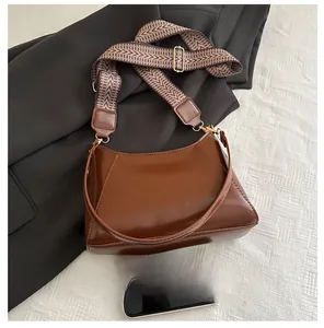 Brown leather crescent bag size comparison with a smartphone for scale reference