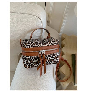 Détail du sac boîte léopard avec double fermeture éclair et franges en cuir sur canapé