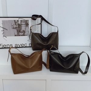 Three minimalist faux leather shoulder bags in black, tan and brown on white steps