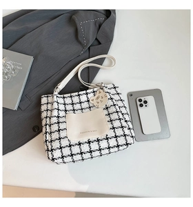 Detail of tweed checkered tote bag featuring a white pocket and a cute cat pendant charm