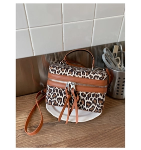 Détail d'un sac bandoulière léopard avec fermetures à franges sur une table en bois