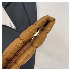 Detail of golden metal zipper and quilted brown nylon fabric on compact storage pouch