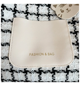 Detail of houndstooth fabric texture with cream faux leather patch and stitched accents