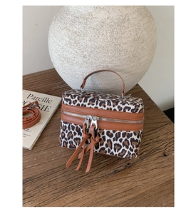 Détail d'un sac à main léopard avec finitions en cuir et double fermeture éclair sur bois