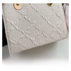 Detail of pink handbag with textured floral jacquard fabric and gold metal hardware