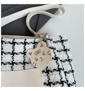 Detail of black and white houndstooth fabric with cream leather trim and tiger charm