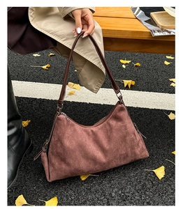 Détail d'un sac à bandoulière en daim marron avec cordon latéral sur fond d'automne
