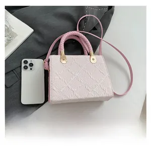 Macro detail of pink square bag showing quilted texture, woven handle and gold hardware