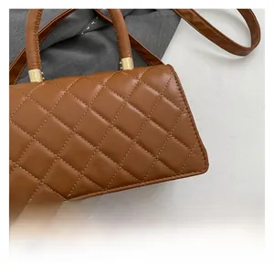 Detalle de bolso acolchado marrón con elegantes conectores de metal dorado en el mango