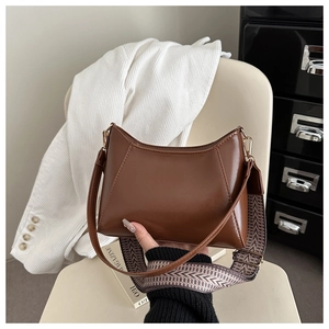 Detail einer braunen Tasche mit V-Nahtmuster und ethnischem Web-Schultergurt