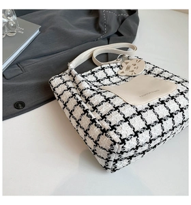 Detail of tweed houndstooth tote bag featuring a cute cat pocket and leather charm