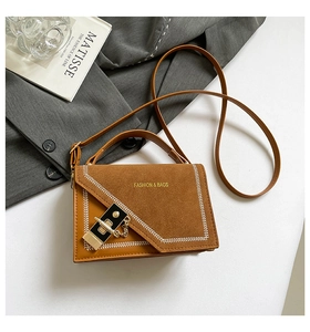 Détail du sac bandoulière en cuir marron avec fermoir doré et coutures tissées