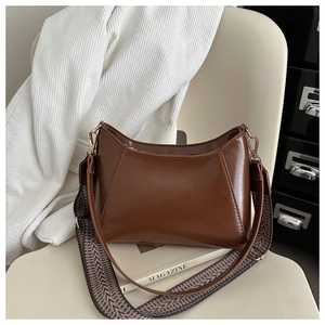 Close-up of brown PU leather shoulder bag with textured jacquard strap on a white chair