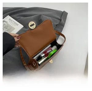 Detalle del interior del bolso de cuero marrón mostrando capacidad para móvil y aseo