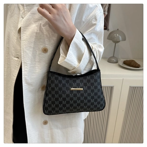 Close-up of black baguette underarm bag with grey M pattern print and gold hardware