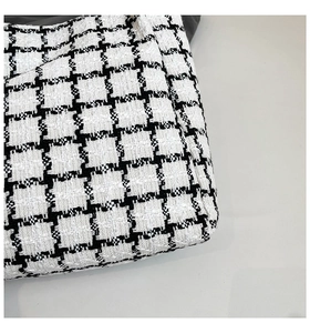 Close-up of premium black and white checkered tweed fabric texture on a tote bag