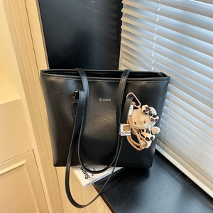 Minimalist black leather tote bag with silver logo and leopard print bear charm