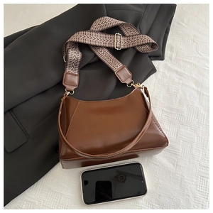 Detail view of large brown shoulder tote bag with patterned strap and leather strap