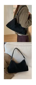 Détail du sac bandoulière vintage en daim noir mat avec bandoulière en cuir sur canapé